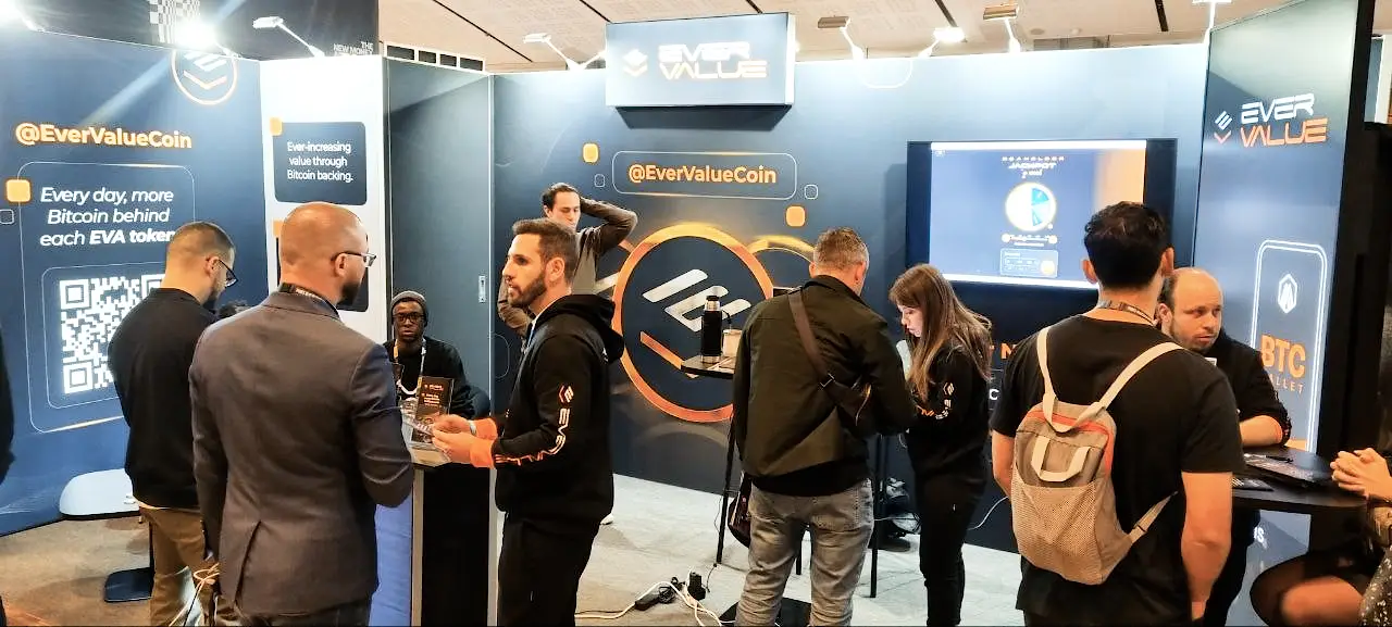 EverValue project booth at Paris Blockchain Week featuring Bitcoin-backed token displays and promotional screens
