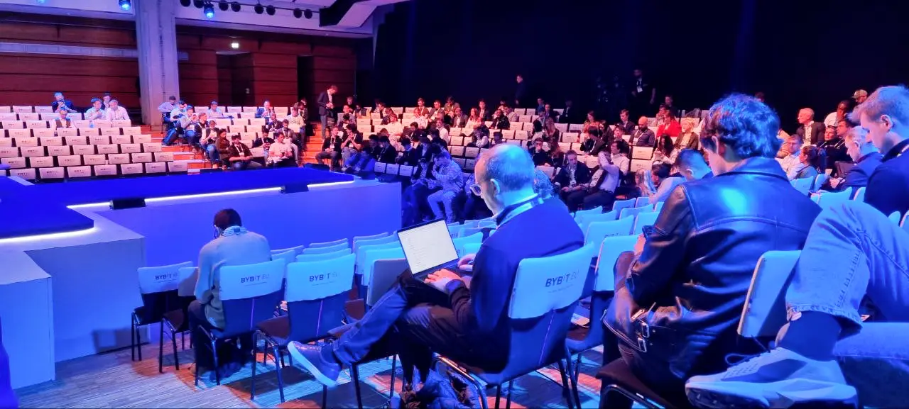View of the main conference stage and auditorium at Paris Blockchain Week, with attendees seated and listening to speakers.