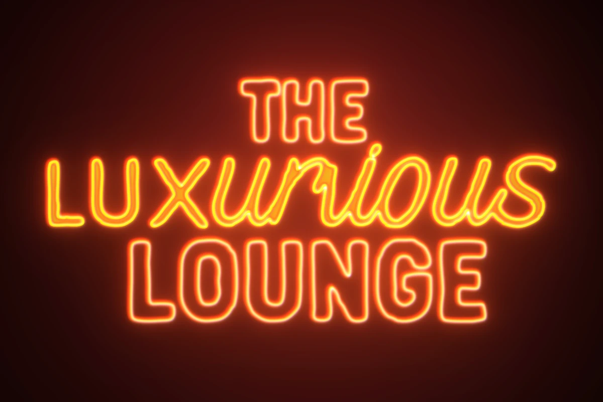 A glowing orange and yellow neon sign displaying the text "THE LUXURIOUS LOUNGE" against a dark, elegant background
